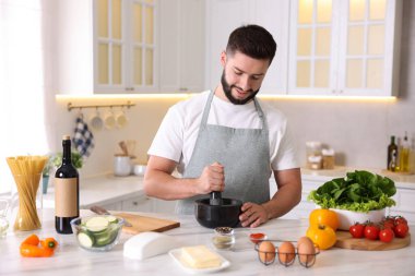 Mutfaktaki masada yemek pişiren gülümseyen adam.