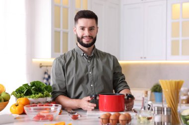 Mutfaktaki masada yemek pişiren gülümseyen adam.
