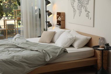 Yatak odasının penceresinin yanında büyük bir yatak, sehpa ve lamba. İç tasarım