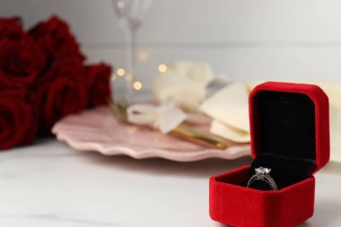 Romantik bir akşam yemeği. Nişan yüzüğünün olduğu kutu beyaz masada, yakın plan. Metin için boşluk