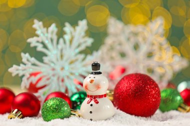 Güzel dekoratif kardan adam ve yapay kar üzerinde parlak mücevherler bulanık ışıklara karşı, yakın plan.