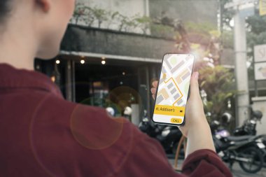 Şehir caddesinde taksi çağırmak için cep telefonu uygulaması kullanan bir kadın.