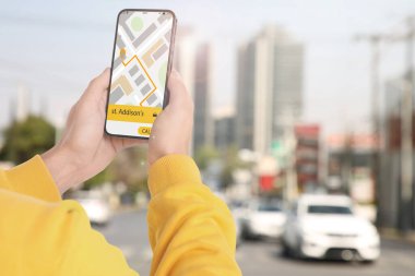 Şehir caddesinde taksi çağırmak için cep telefonu uygulaması kullanan bir adam.