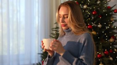 Evdeki Noel ağacının yanında kakao kokan bir kadın. Kamera ona doğru geliyor.