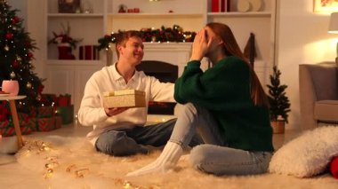 Adam, süslü püslü odada sevgilisine Noel hediyesi veriyor.