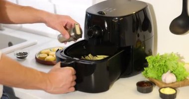 Beyaz mermer tezgahta patates kızartmasına baharat ekleyen adam, yakın plan. Kamera içeri giriyor.