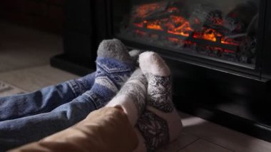 Sıcak çoraplı çift şöminenin yanında dinleniyor, yakın çekim. Kamera içeri giriyor.