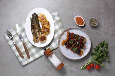 Gri masada servis edilen lezzetli ızgara sebzeli şişler.