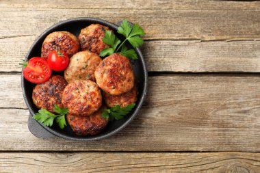 Maydanozlu leziz köfteler ve tavada domatesler, ahşap masa, üst manzara. Metin için boşluk