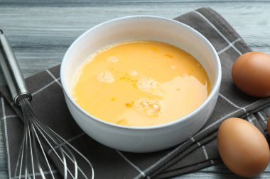 Kavanozda çırpılmış yumurtalar ve ahşap masada çırpılmış çırpılmış çırpılmış çırpma, yakın plan.