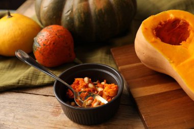 Fresh pumpkins and seeds on wooden table, closeup