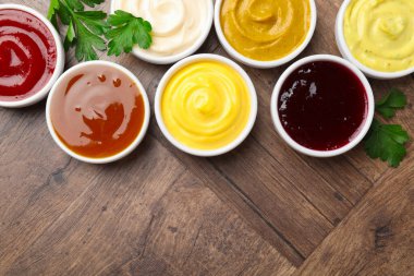 Tabaklardaki farklı lezzetli soslar ve ahşap masada maydanoz. Metin için boşluk