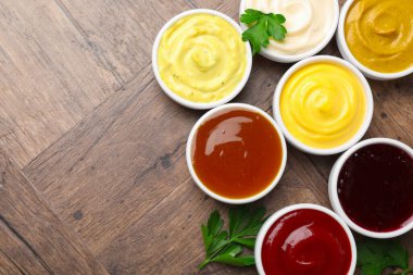 Tabaklardaki farklı lezzetli soslar ve ahşap masada maydanoz. Metin için boşluk