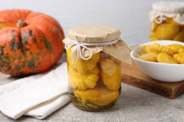 Kavanozda turşu kabağı turşusu, kabak ve kabak, gri desenli masa, arka planda ışık, yakın plan.