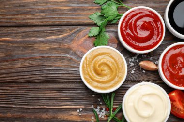 Farklı soslar, baharatlar ve otlar ahşap masada, düz yerde. Metin için boşluk