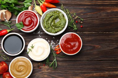 Farklı soslar, baharatlar ve otlar ahşap masada, düz yerde. Metin için boşluk