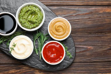 Farklı soslar ve otlar ahşap masada, düz yerde. Metin için boşluk