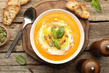 Tahta masada servis edilen fesleğenli ve tohumlu lezzetli balkabağı kremalı çorba.