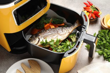 Lezzetli ızgara balık, sebze ve baharatlı kızartma makinesi. Gri masada, yakın plan.