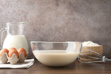 Tabakta sıvı hamur, çırpma ve malzemeler ahşap masada, yakın plan.