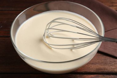 Sıvı hamur kasede ve çırpı ahşap masada, yakın plan.