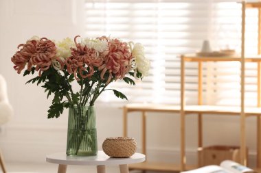 İçerideki sehpada vazoda güzel kasımpatı çiçekleri, metin için yer.