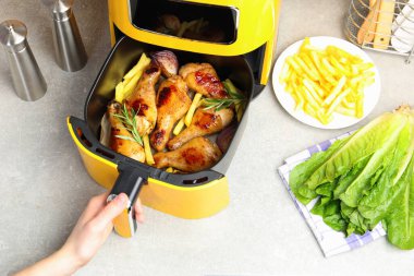 Gri masada tavuklu tavuk budu pişiren bir kadın.