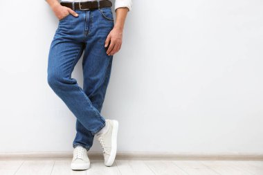 Beyaz duvarın yanında şık kotlu bir adam, yakın plan. Metin için boşluk