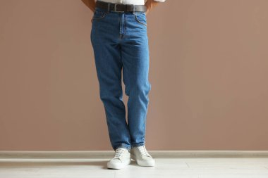 Bej duvarın yanında şık kotlu bir adam, yakın plan.