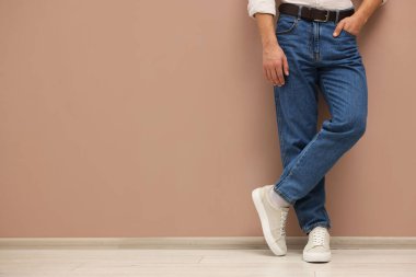 Bej duvarın yanında şık kotlu bir adam, yakın plan. Metin için boşluk