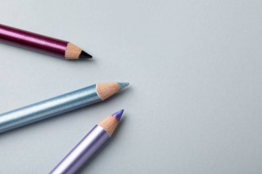 Işık arkaplan üzerinde renkli göz kalemleri, görüntünün üstünde. Metin için boşluk