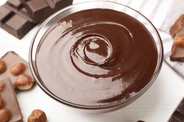 Erimiş çikolata ve fındıklı beyaz tahta masa, yakın plan.