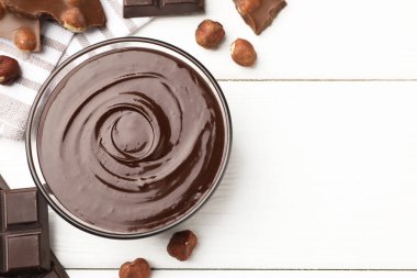 Erimiş çikolata ve fındıklı beyaz ahşap masa, düz. Metin için boşluk
