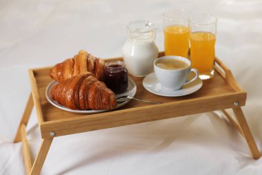 Otel odasındaki yatakta nefis bir kahvaltı tepsisi, yakın plan.