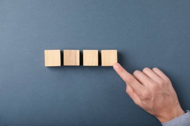 Gri arka planda tahta küpleri olan adam, üst manzara.