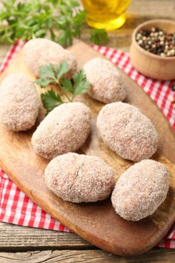 Pişmemiş köfteler, maydanozlar, biberler ve ahşap masa üzerindeki yağlar, yakın plan.