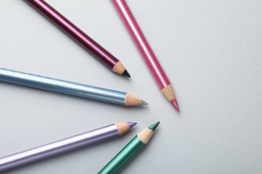 Hafif arka planda renkli göz kalemleri, düz yatış. Metin için boşluk