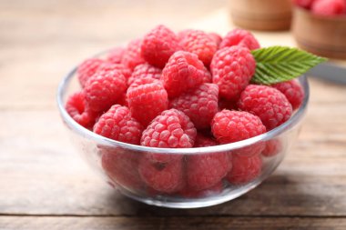 Tahta masadaki kasede taze olgun ahududular, yakın plan.