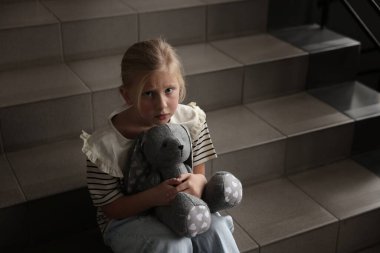 Oyuncak tavşancığı olan üzgün küçük kız merdivenlerde ağlıyor, mesaj atmak için yer var.