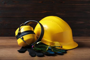 Sert şapka, koruyucu eldivenler, gözlükler ve ahşap masadaki kulaklıklar. Güvenlik ekipmanları