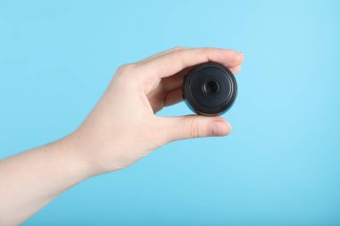 Açık mavi arka planda gizli casus kamerası olan kadın, yakın plan.