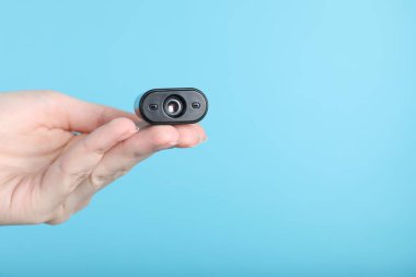 Açık mavi arka planda gizli casus kamerası olan kadın, yakın plan. Metin için boşluk