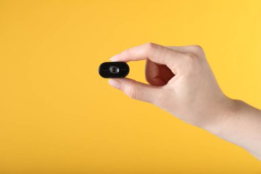 Sarı arka planda gizli casus kamerası olan kadın, yakın plan. Metin için boşluk