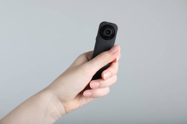 Açık gri arka planda gizli casus kamerası olan kadın, yakın plan.