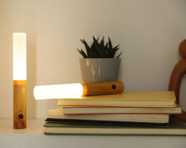 Portatif LED lambalar, kitaplar ve dekorlar beyaz rafta, yakın plan