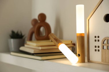 Portatif LED lambalar, kitaplar ve dekorlar beyaz rafta, yakın plan