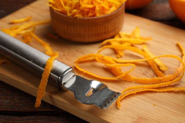 Taze portakal hazzı ve zester aleti ahşap masada, yakın plan.