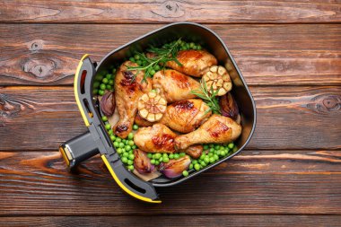 Kızarmış tavuk budu, baharat ve ahşap masada yeşil bezelye sepeti.