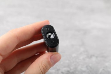 Açık gri masada elinde modern casus kamerası olan bir kadın. Yakın plan.