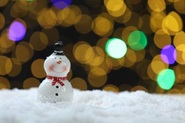 Bulanık ışıklara karşı yapay kar üzerinde sevimli bir kardan adam, yakın plan. Metin için boşluk